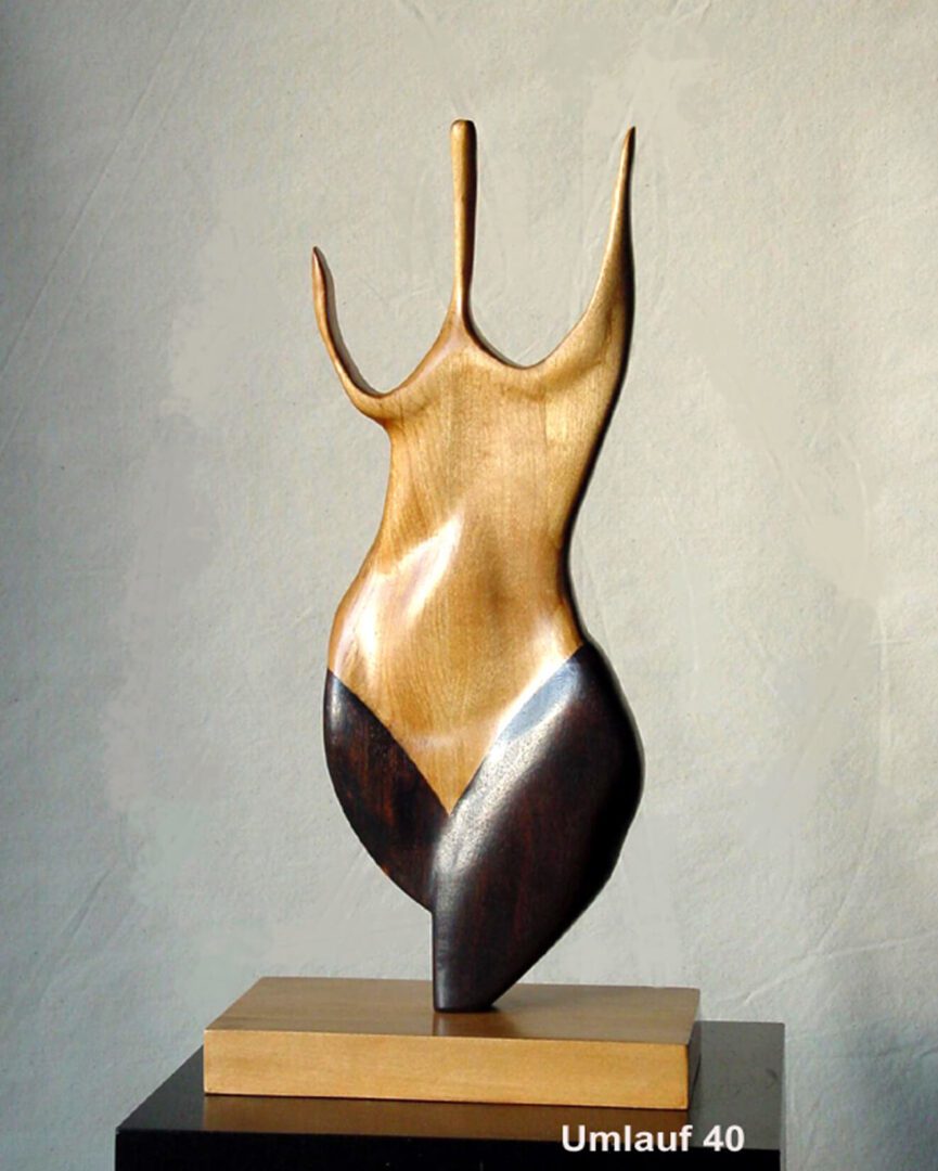 A wooden sculpture of a woman 's body on top of a table.