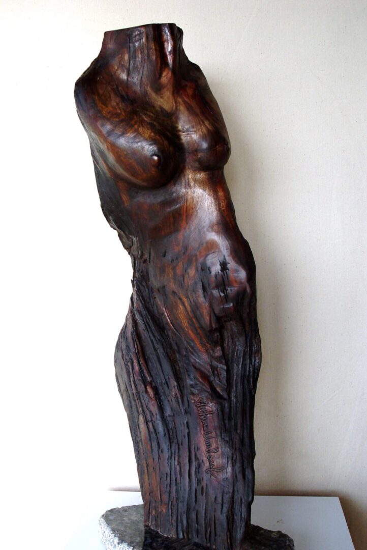 A wooden statue of a man 's torso leaning against the wall.