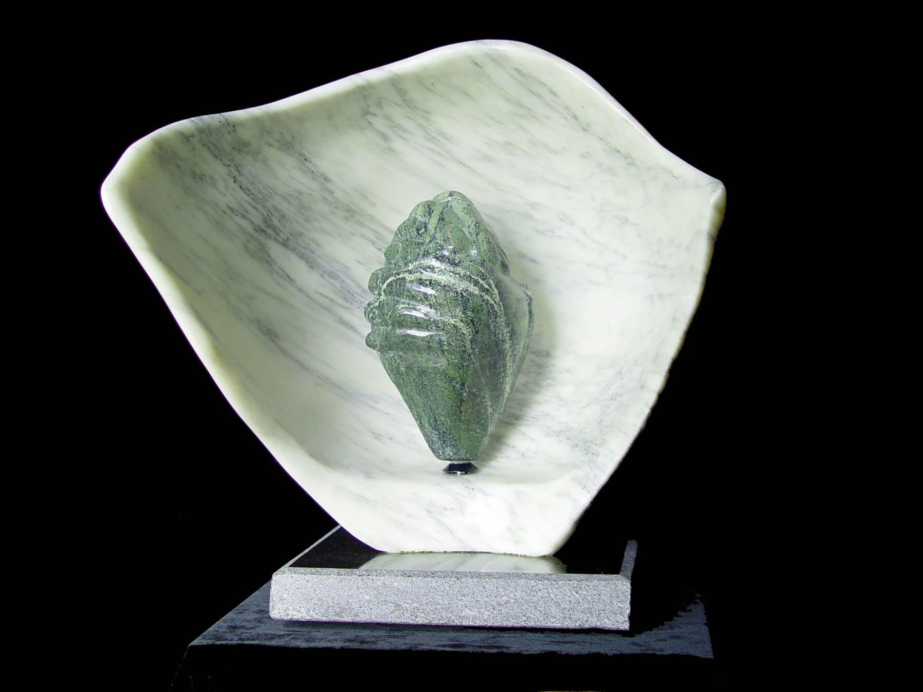 A marble sculpture of a leaf on top of a black base.