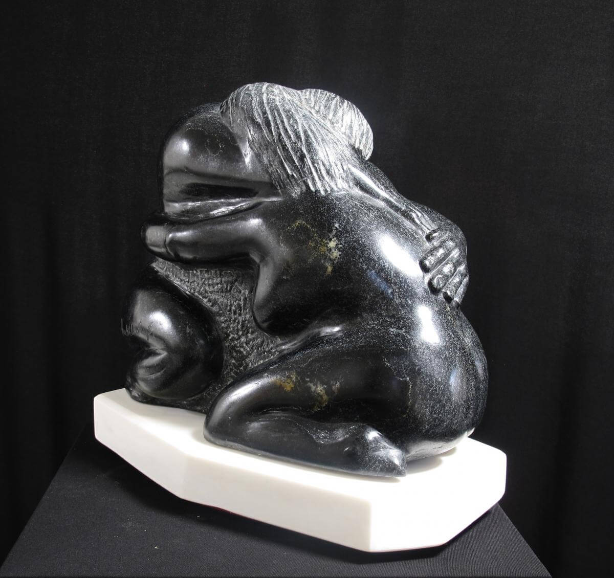 A black stone sculpture of a person hugging another
