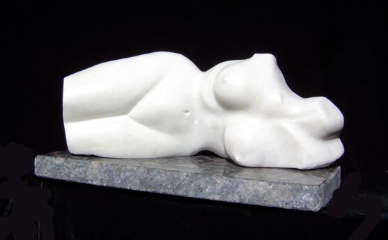 A white statue of a woman laying on the ground.