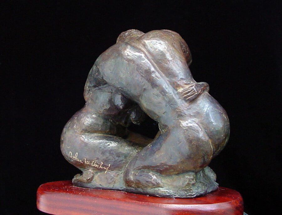 A bronze statue of a man sitting on top of a wooden table.