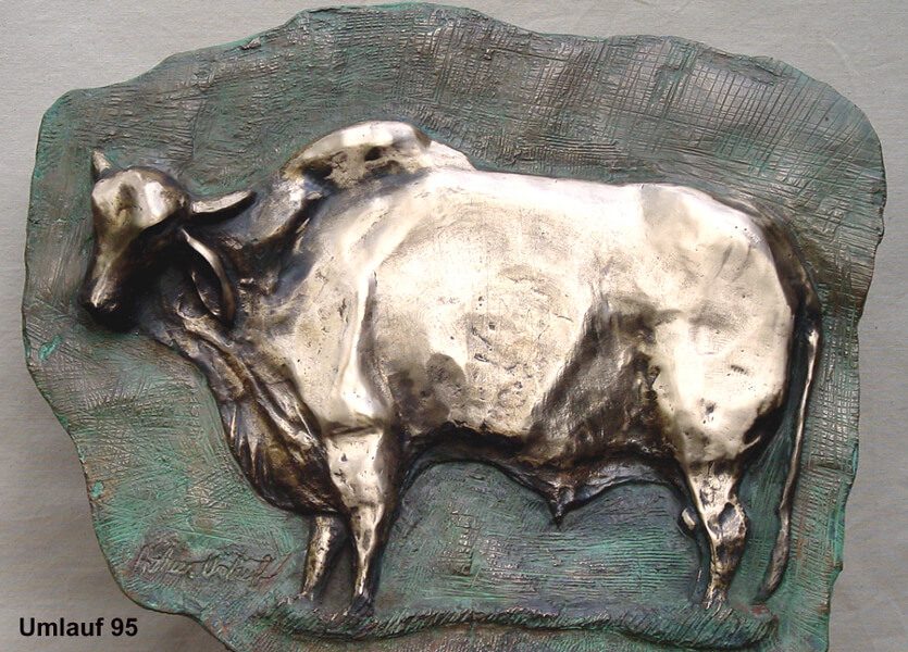 A silver bull statue on top of a rock.
