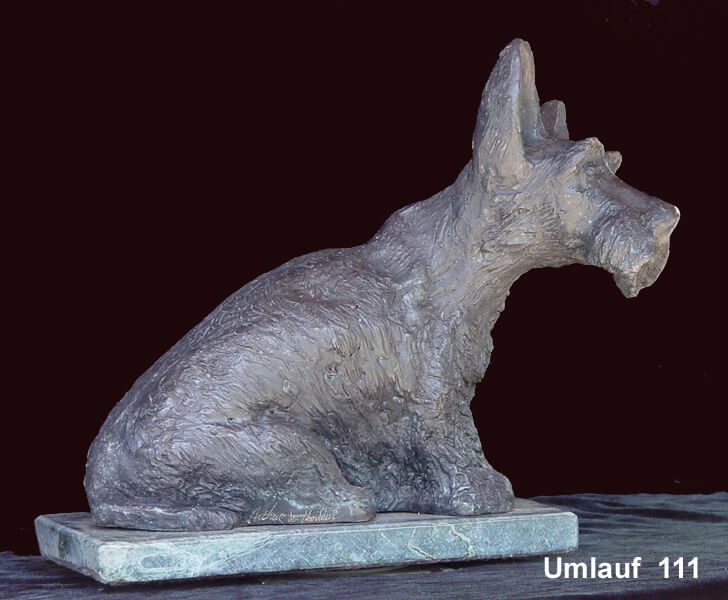 A dog statue sitting on top of a wooden block.