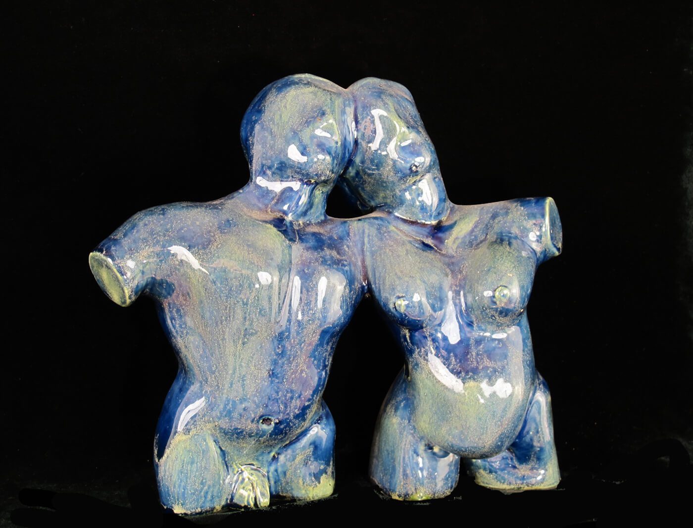 Two blue ceramic figures are hugging each other.