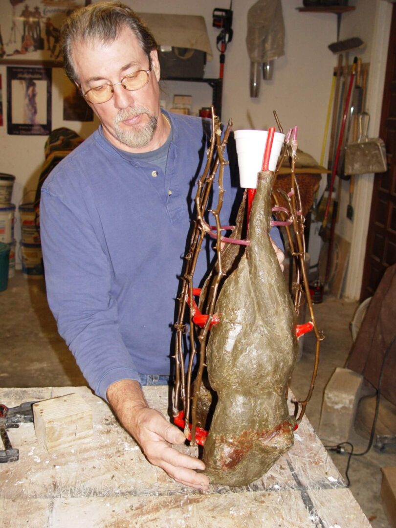 A man working on a vase with red and brown sticks.