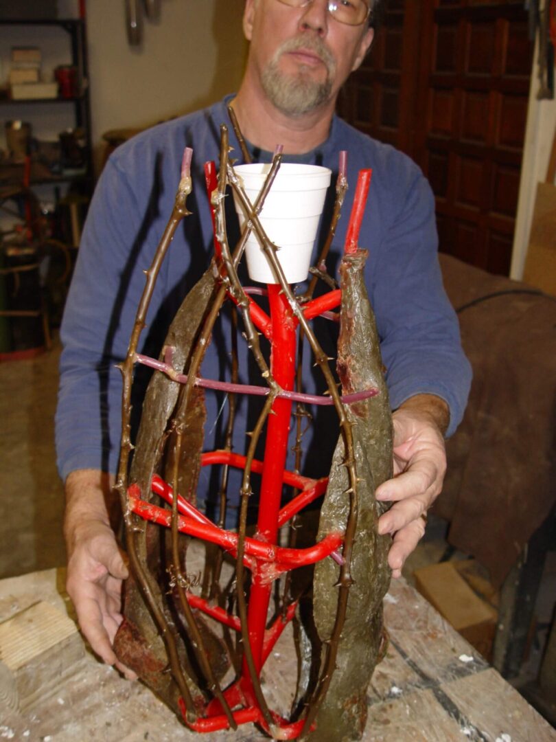 A man holding sticks and branches in his hands.