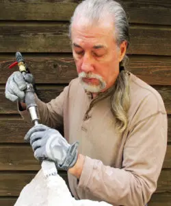 A man holding an old pipe with a wrench.