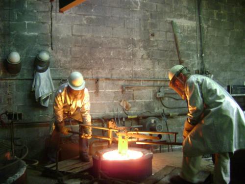 Two men working in a foundry with an open fire.