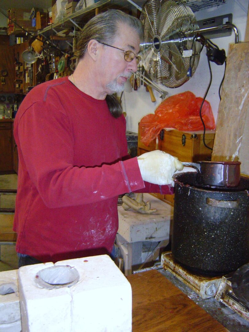 A man wearing a red shirt making a mother mold.