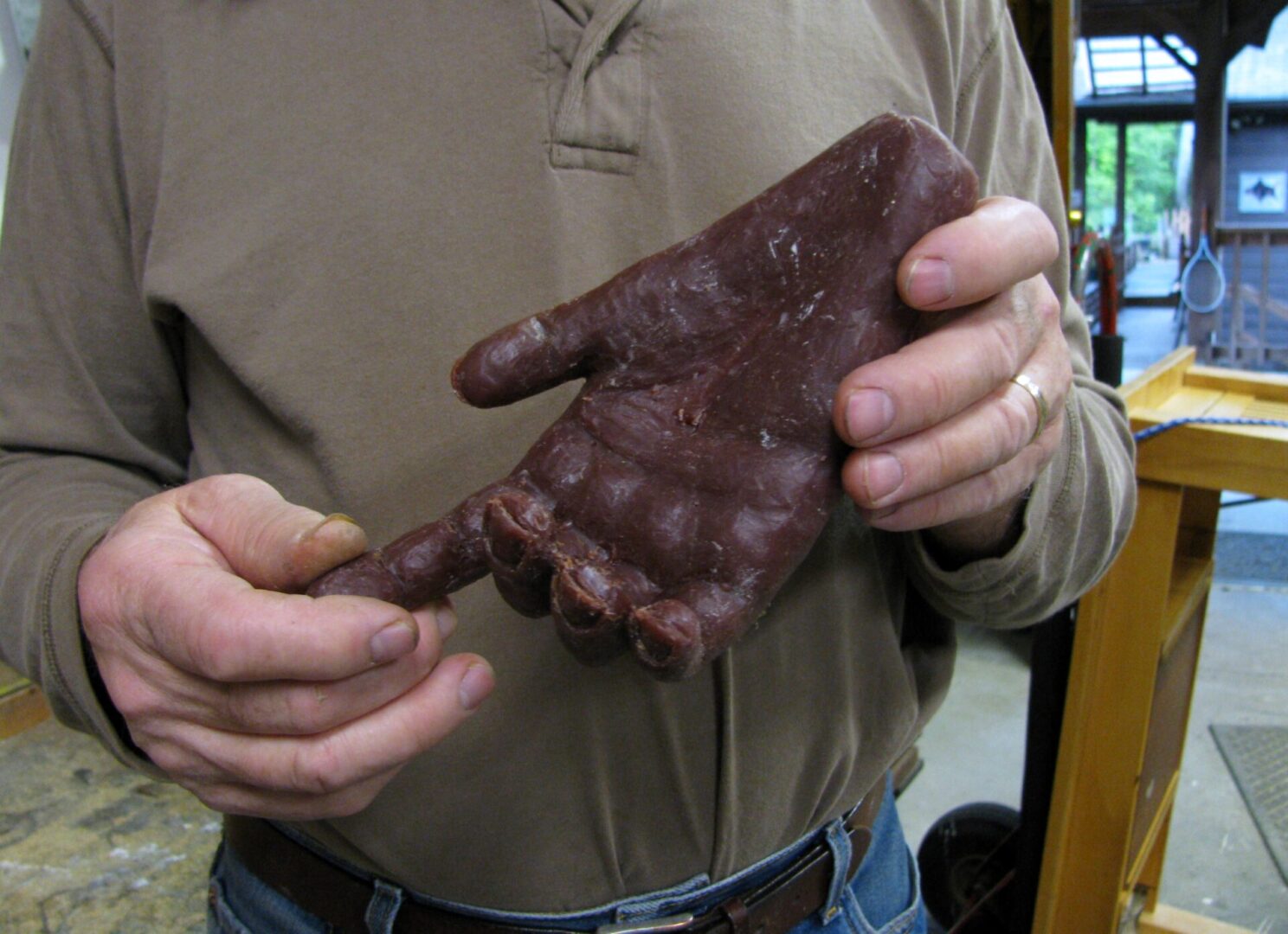A man making a Mother Mold, while holding a piece of chocolate.