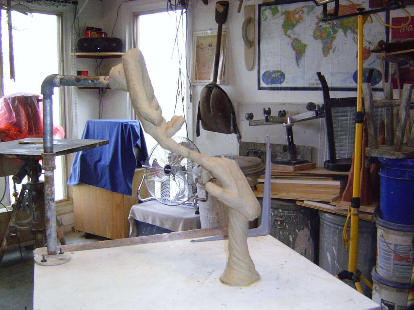 A wooden sculpture on a table in a workshop, being transformed as the artist carefully creates a mother mold.