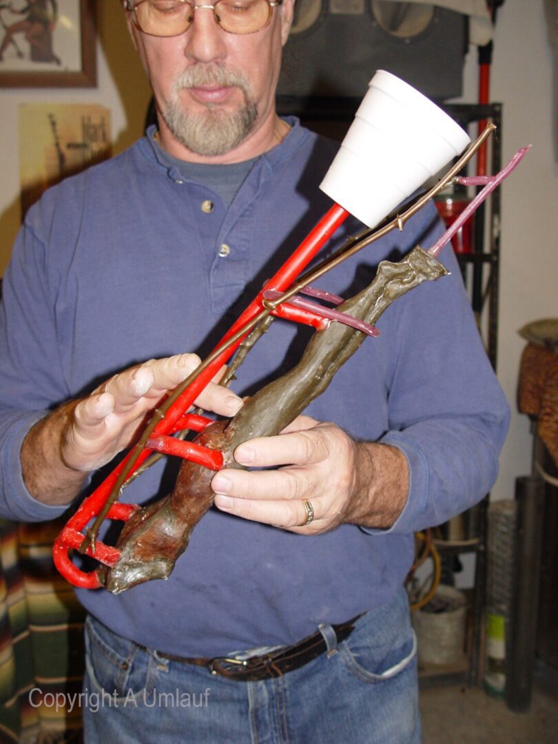 A man holding a trombone created using the investment mold method.