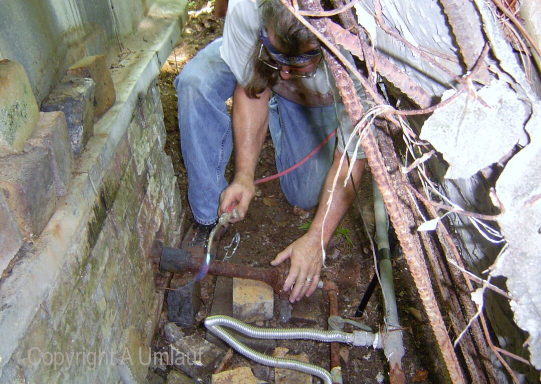 A man utilizing the investment mold method to repair a pipe in an old house.