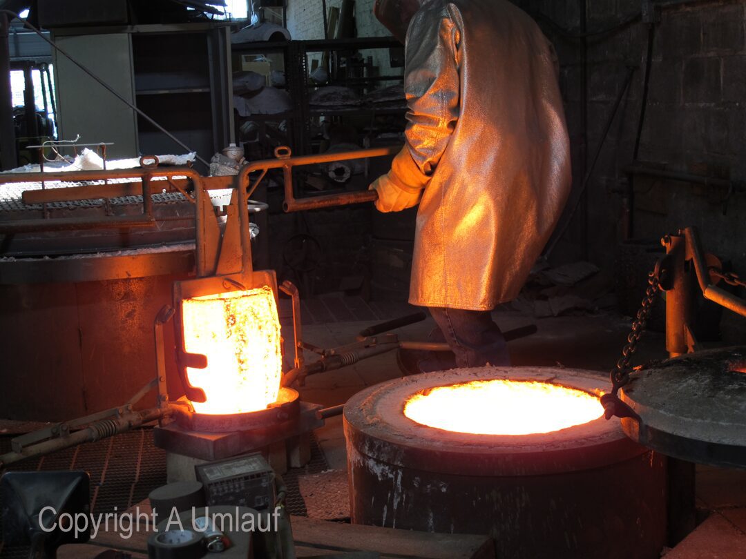 A man working in a factory pouring bronze.