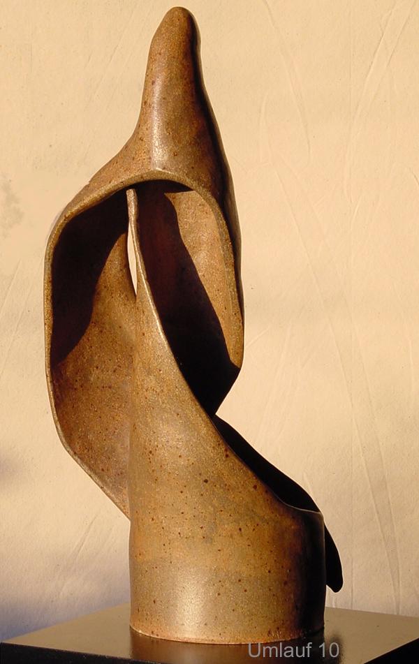 A Umlauf sculpture showcasing a brown masterpiece, elegantly displayed on a wooden base.