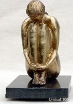 A bronze sculpture of a woman sitting on a black base displayed at a Fine Art Gallery.