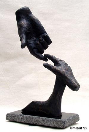 A breathtaking bronze sculpture of two hands reaching for each other on display at a Fine Art Gallery.