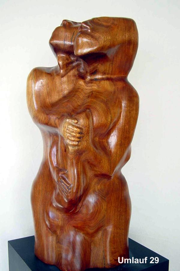 A wooden sculpture of a woman holding a baby, part of the Sculpture Collection.
