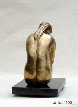 A gold statue of a woman on a black base displayed in a Fine Art Gallery.