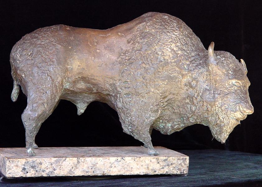 A bronze statue of a bison on a marble base displayed in a Fine Art Gallery.