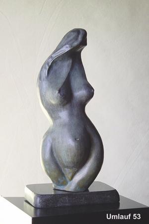 A bronze sculpture of a woman sitting on a table displayed in a Fine Art Gallery.