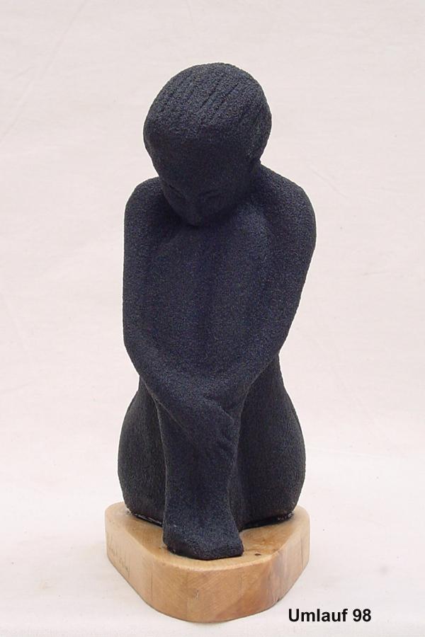 An exquisite black sculpture of a woman sitting on a wooden base, showcasing its beauty and elegance at an art gallery exhibition.